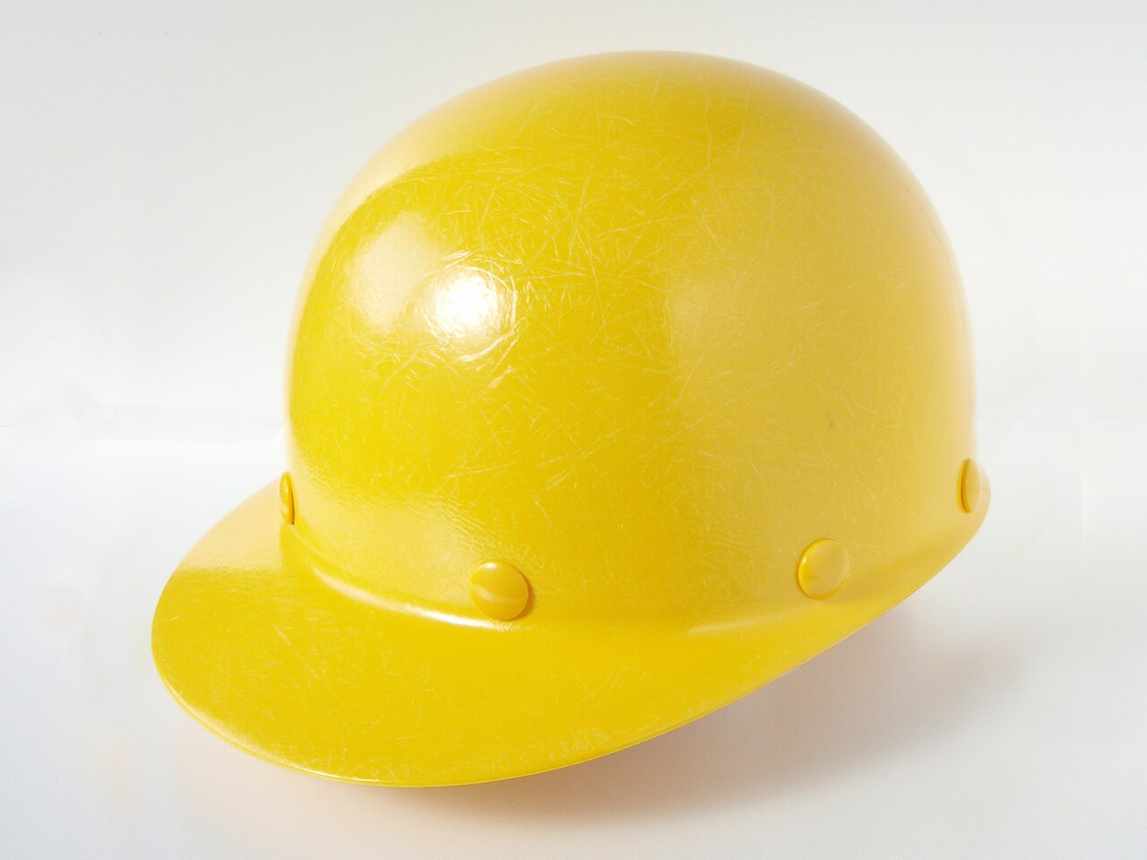 A yellow fibreglass hard hat on a white background.